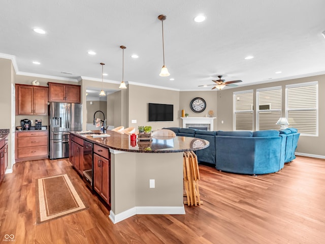 kitchen featuring light wood-style flooring, stainless steel fridge with ice dispenser, a sink, a ceiling fan, and crown molding
