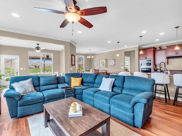 living room featuring light wood-type flooring, ornamental molding, recessed lighting, and plenty of natural light