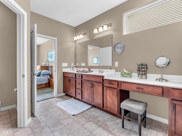 full bath featuring double vanity, connected bathroom, and baseboards