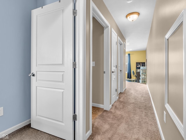 hall featuring light colored carpet and baseboards
