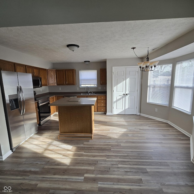kitchen with a textured ceiling, stainless steel appliances, a notable chandelier, and a sink