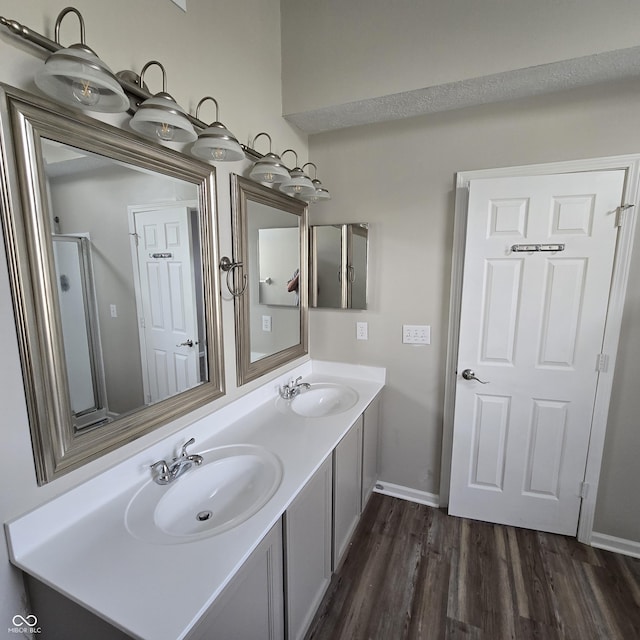 full bathroom with double vanity, a sink, wood finished floors, and baseboards