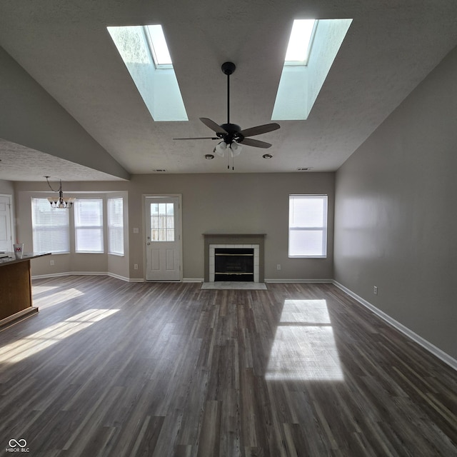 unfurnished living room featuring baseboards, a skylight, a tile fireplace, and dark wood-style flooring
