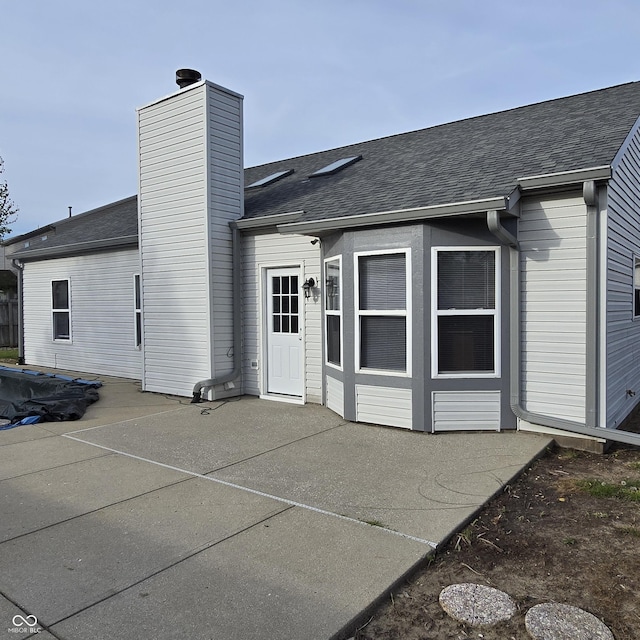back of house featuring a patio and roof with shingles