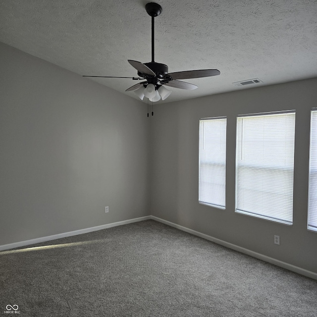 carpeted empty room featuring baseboards, visible vents, a ceiling fan, and a textured ceiling