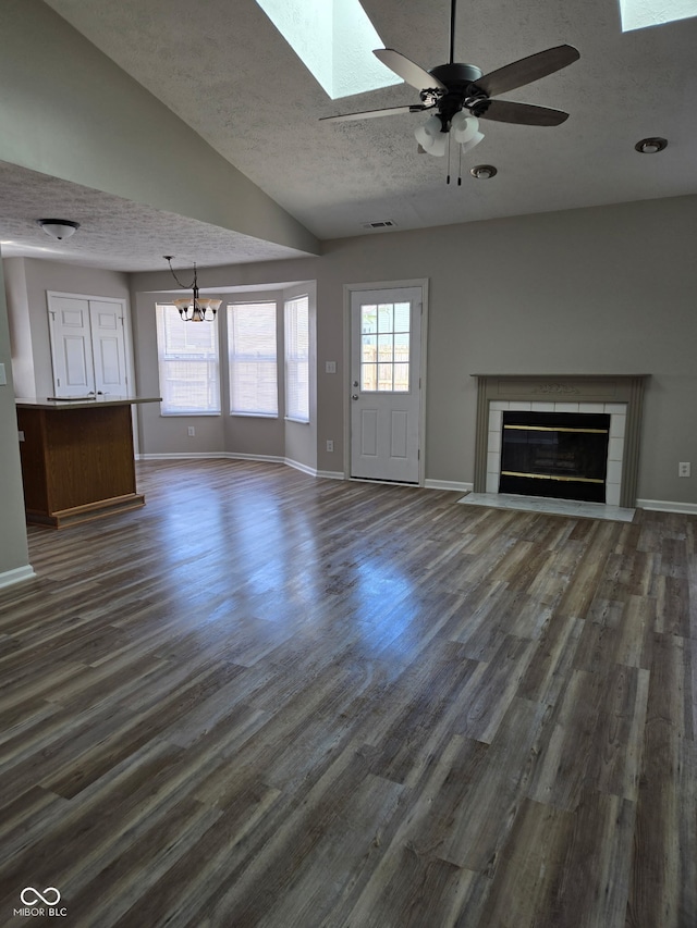 unfurnished living room with dark wood-style floors, a skylight, a textured ceiling, and a fireplace