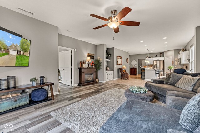 4809 Ozark Ln, Indianapolis, IN 46239 - living room featuring recessed lighting, a glass covered fireplace, light wood-type flooring, a ceiling fan, and visible vents