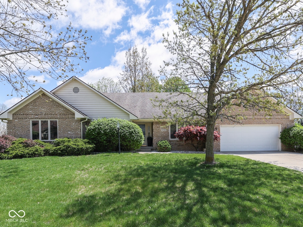 ranch-style home featuring a garage, brick siding, a front lawn, and concrete driveway