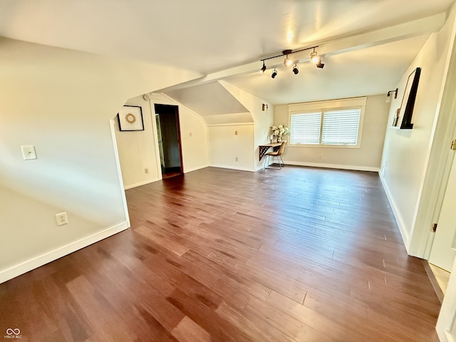 unfurnished living room with baseboards, dark wood-type flooring, and vaulted ceiling