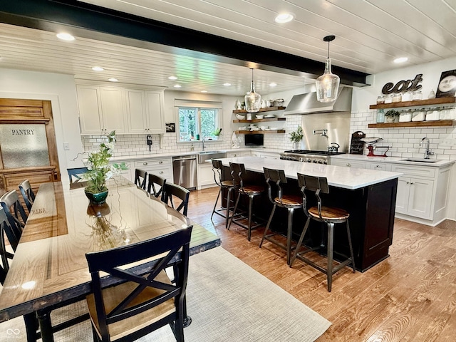 interior space with a sink, open shelves, light wood-style flooring, dishwasher, and white cabinets