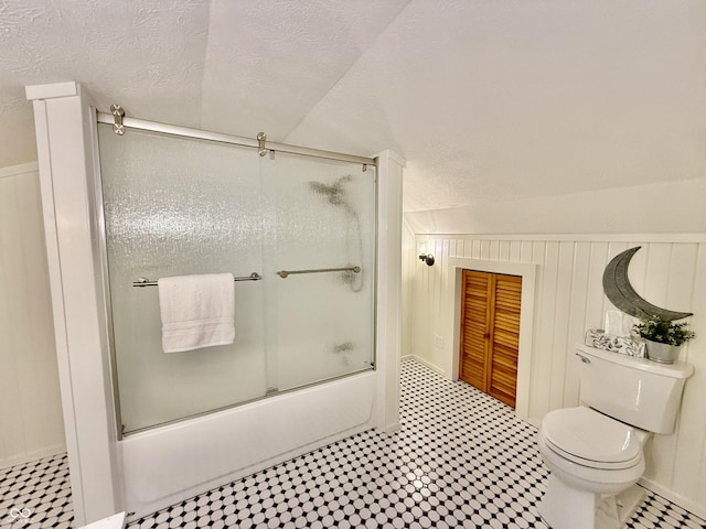 full bath featuring tile patterned floors, shower / bath combination with glass door, toilet, and a textured ceiling