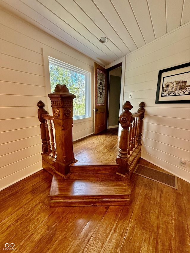 corridor featuring baseboards, wood walls, and hardwood / wood-style flooring