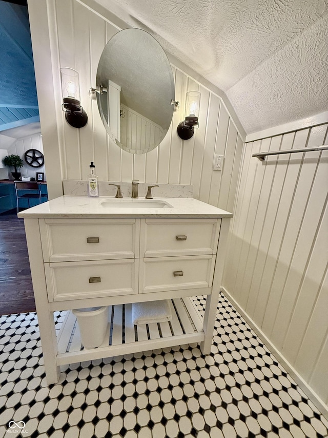 bathroom featuring a textured ceiling, vaulted ceiling, and vanity