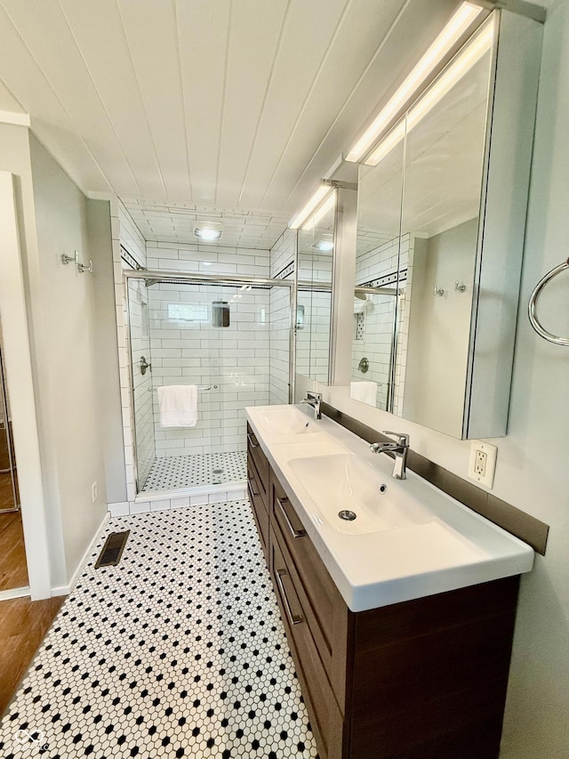 full bathroom featuring double vanity, visible vents, a shower stall, and a sink