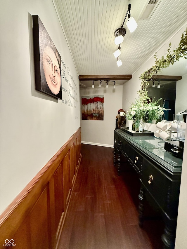 hallway featuring rail lighting, dark wood-type flooring, visible vents, and wainscoting