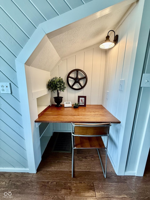 dining area featuring lofted ceiling, a textured ceiling, and wood finished floors