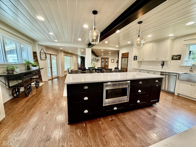 kitchen with dark cabinetry, white cabinetry, a kitchen island, hardwood / wood-style floors, and appliances with stainless steel finishes