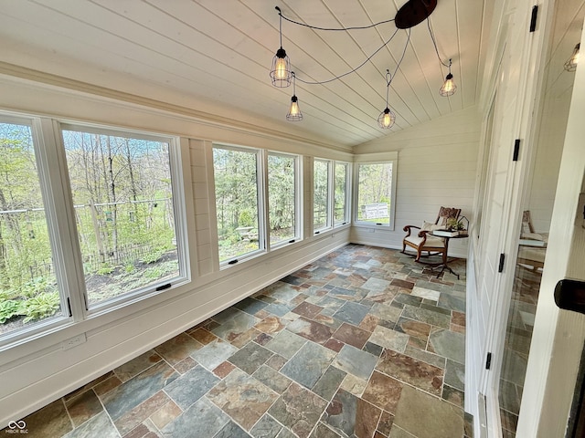 sunroom with stone tile floors and vaulted ceiling