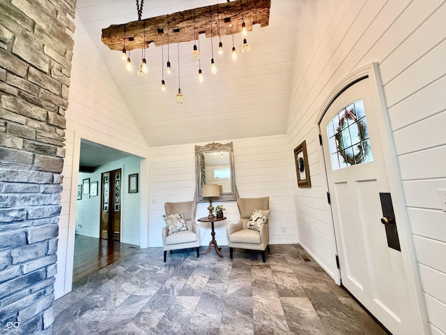 foyer featuring wood walls, stone finish flooring, and lofted ceiling