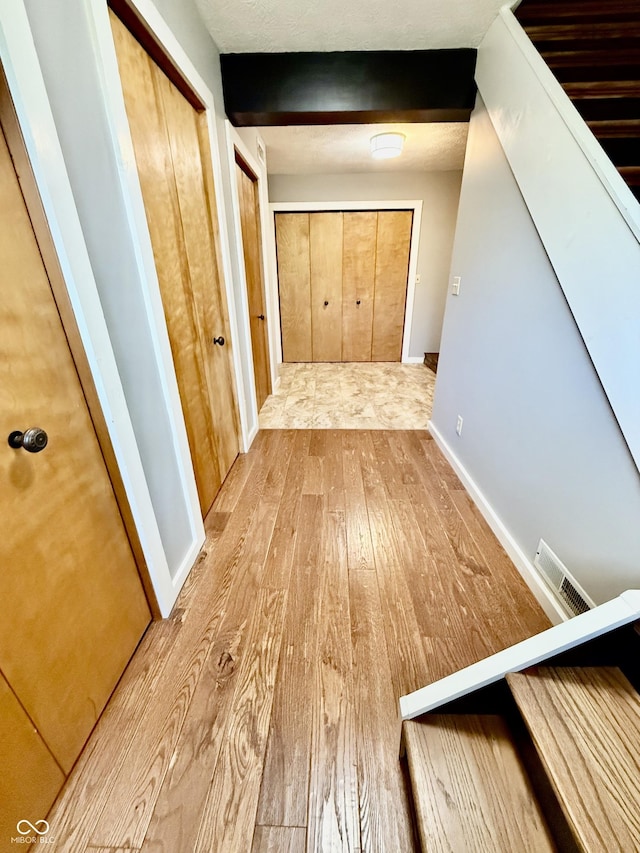 hallway with wood-type flooring and visible vents