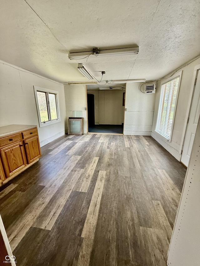 unfurnished living room with a textured ceiling, a wealth of natural light, and dark wood-type flooring