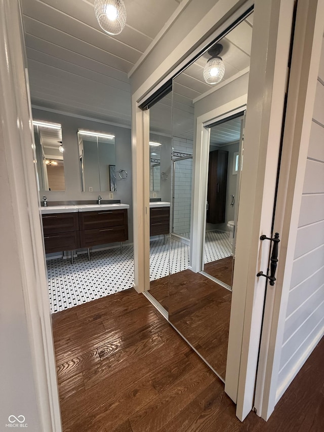 bathroom with double vanity, ornamental molding, toilet, wood-type flooring, and a sink