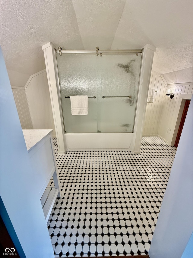 bathroom featuring a textured ceiling, vanity, tile patterned flooring, and shower / bath combination with glass door
