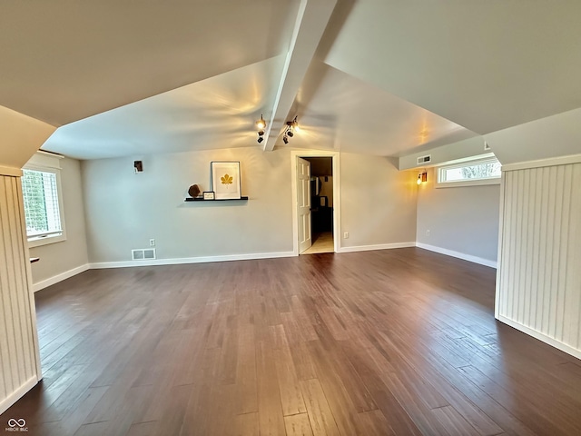 unfurnished living room featuring plenty of natural light, visible vents, vaulted ceiling, and dark wood-type flooring