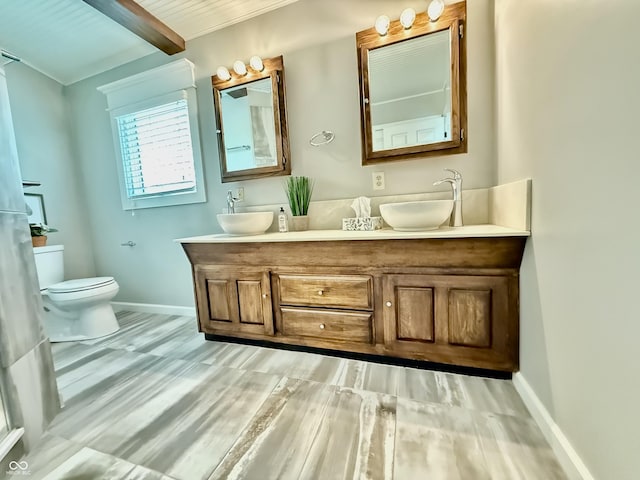bathroom with double vanity, toilet, baseboards, and a sink