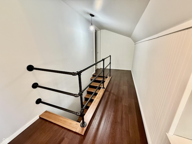 staircase featuring baseboards, wood finished floors, and vaulted ceiling