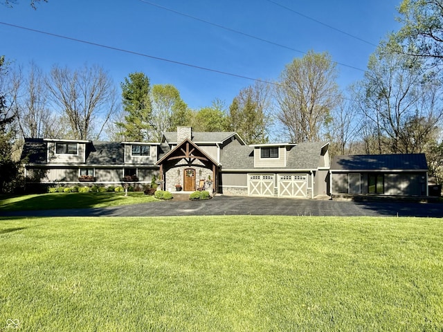 view of front facade with a chimney, stone siding, driveway, roof with shingles, and a front lawn