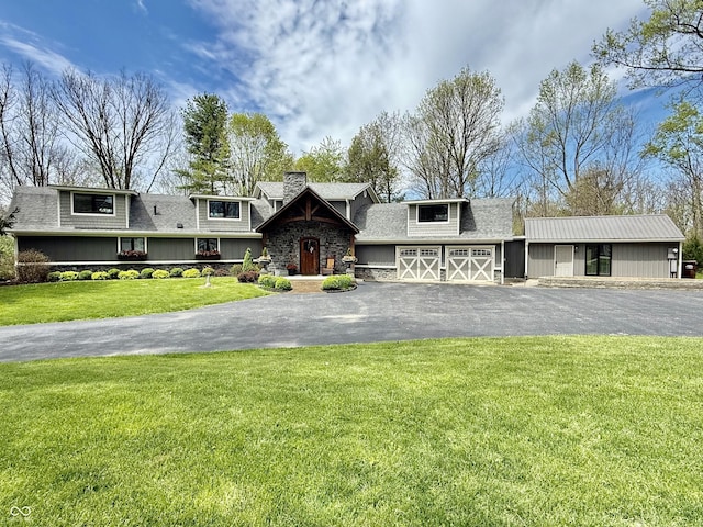 view of front of property with driveway, a chimney, a shingled roof, a front yard, and an attached garage