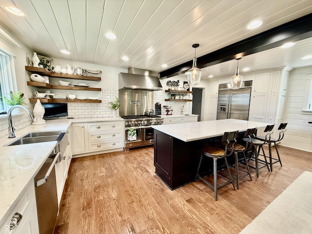 kitchen with wall chimney range hood, open shelves, a sink, recessed lighting, and high end appliances