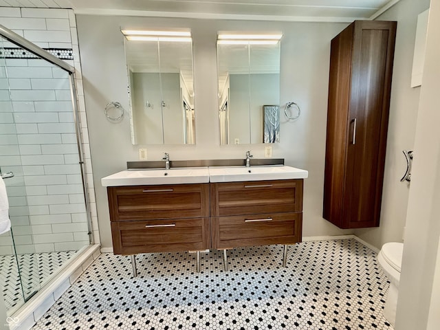 full bathroom featuring a stall shower, toilet, double vanity, and a sink