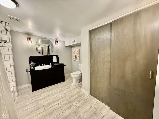 full bath with toilet, visible vents, vanity, and baseboards