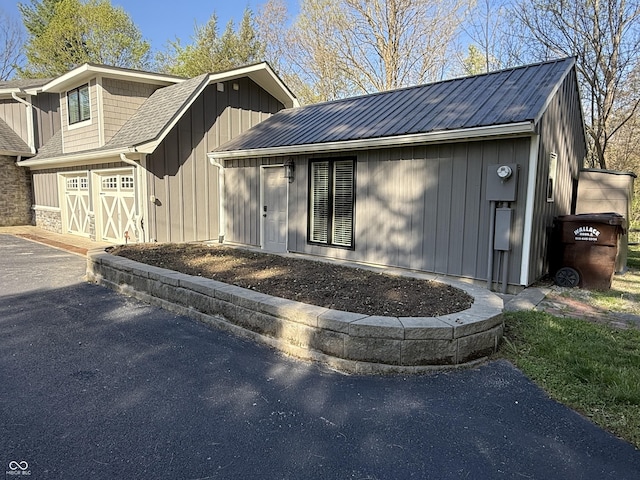 view of front facade with a garage, board and batten siding, driveway, and metal roof