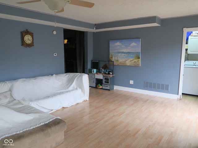 living area featuring baseboards, visible vents, wood finished floors, and a ceiling fan
