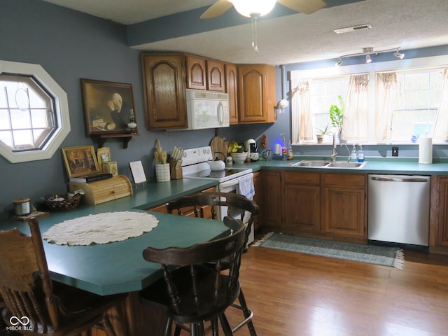 kitchen with a healthy amount of sunlight, brown cabinetry, white appliances, and a sink