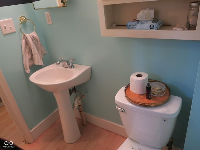 bathroom with toilet, a sink, wood finished floors, and baseboards
