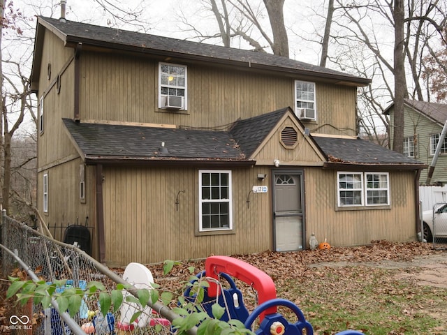 view of front facade featuring roof with shingles and fence