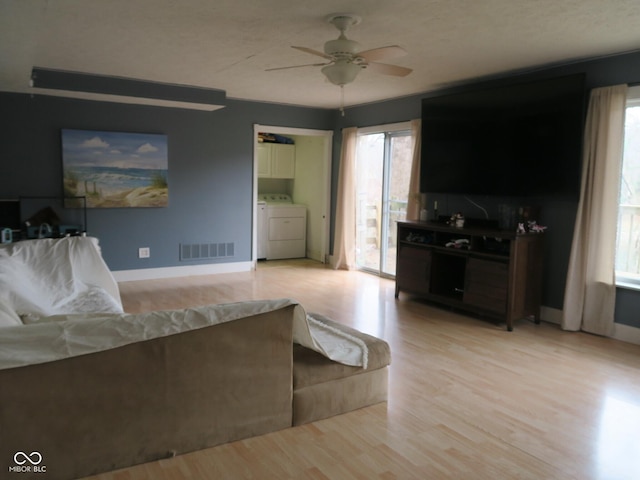 living room with visible vents, separate washer and dryer, light wood-style flooring, and a ceiling fan
