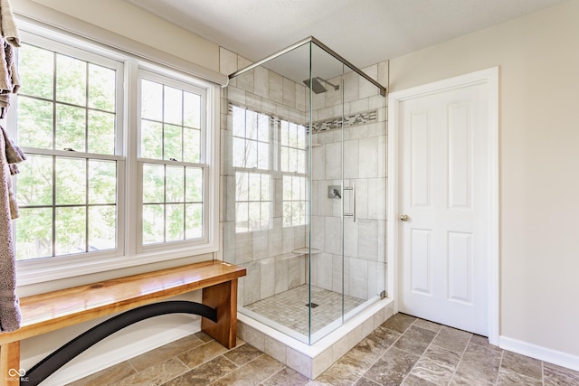 full bathroom with baseboards, stone finish floor, and a shower stall