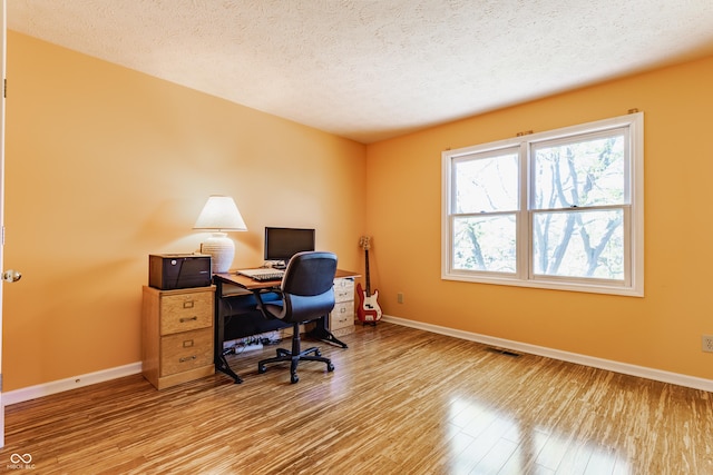 office space with baseboards, a textured ceiling, and wood finished floors