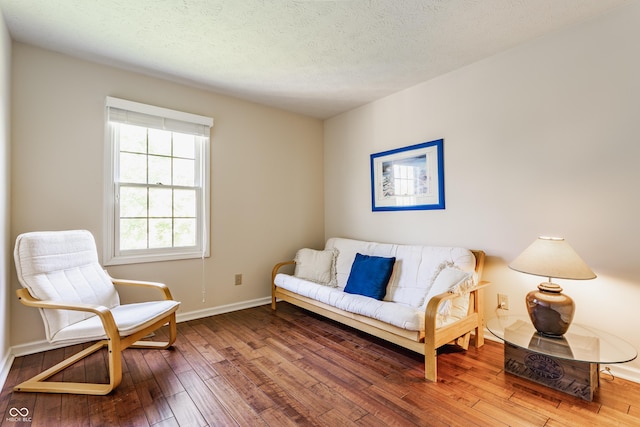 living area with baseboards, a textured ceiling, and hardwood / wood-style floors