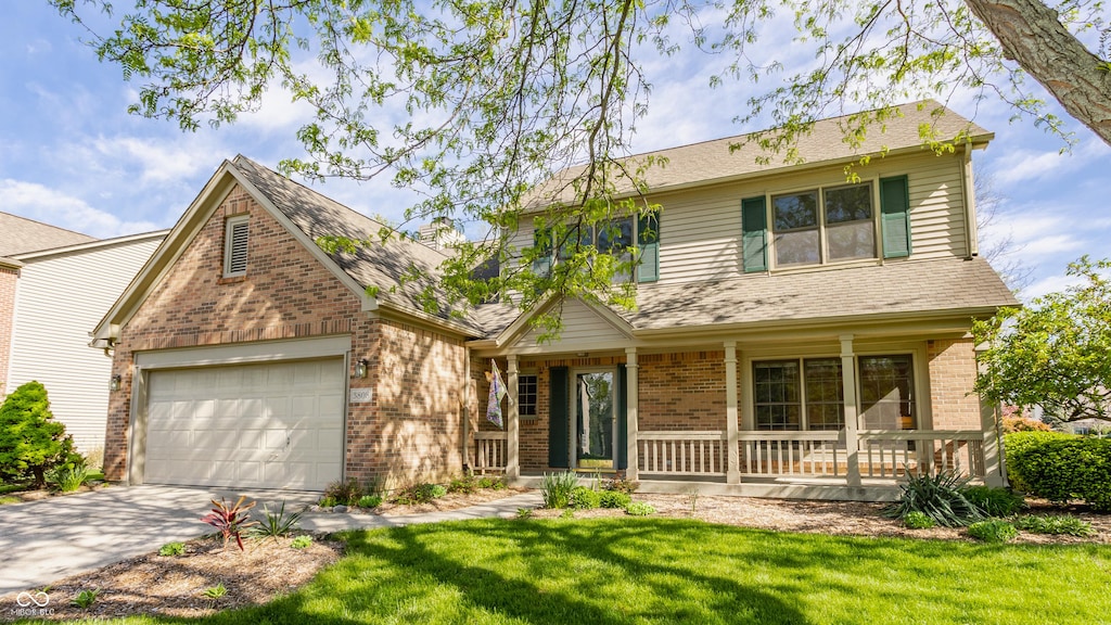 traditional home featuring a garage, concrete driveway, a porch, and brick siding