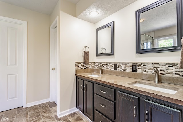 bathroom with baseboards, decorative backsplash, and a sink