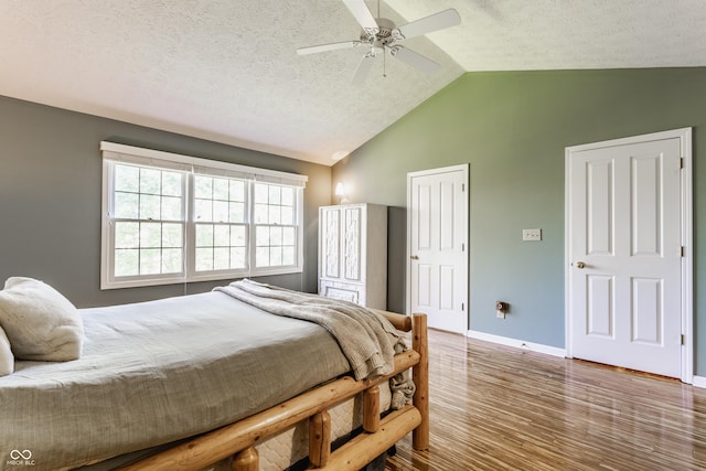 bedroom featuring ceiling fan, a textured ceiling, baseboards, wood finished floors, and vaulted ceiling