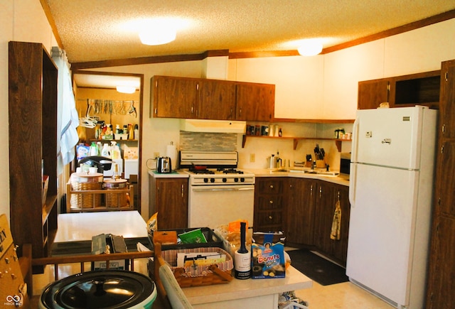 kitchen featuring a sink, under cabinet range hood, white appliances, and light countertops