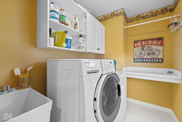 laundry area featuring baseboards, a sink, cabinet space, and washer / clothes dryer