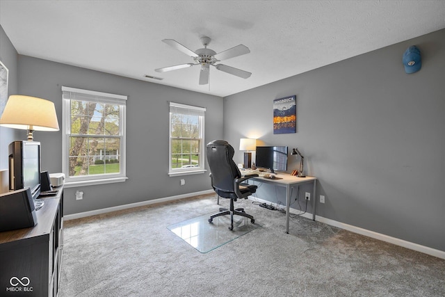 carpeted home office featuring baseboards, a textured ceiling, ceiling fan, and visible vents